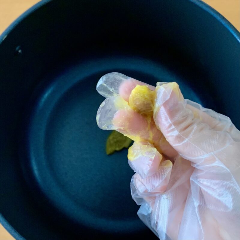 茹でこぼした青梅を手でつぶして種を取り出す様子